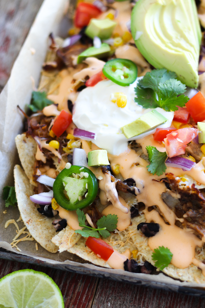 Mouthwatering, easy-to-make sheet pan nachos that are perfect for any party! Your favorite tortilla chips covered with pulled pork and black beans and smothered in beer cheese sauce and loaded with toppings!