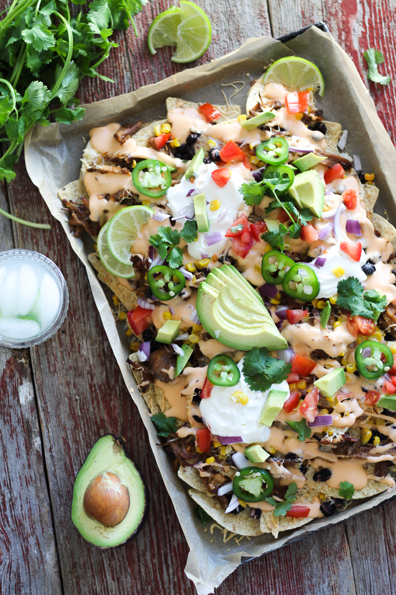 Mouthwatering, easy-to-make sheet pan nachos that are perfect for any party! Your favorite tortilla chips covered with pulled pork and black beans and smothered in beer cheese sauce and loaded with toppings!