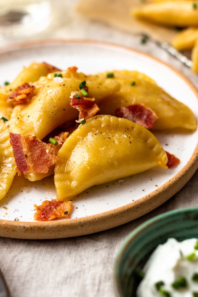 Easy, homemade, tender pasta dough filled with crispy bacon, sharp cheddar cheese and creamy, buttery mashed potatoes. The best comfort food!! Boil the pierogies then sauté in butter and olive oil till golden, delicious perfection. Season with salt and pepper, drizzle with more butter, and top with crumbled bacon and chives.