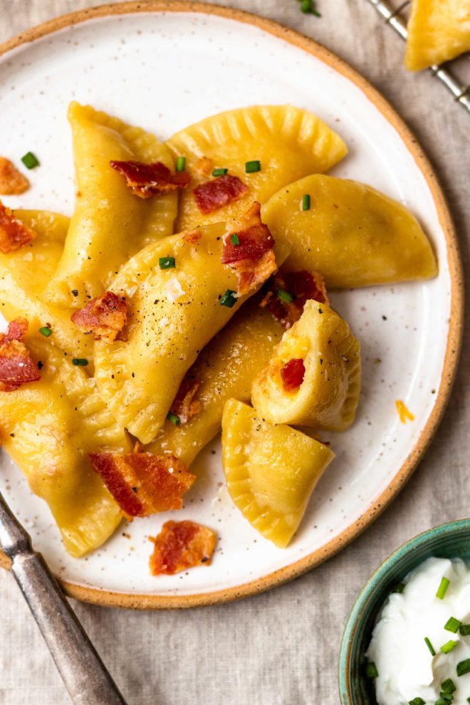 Easy, homemade, tender pasta dough filled with crispy bacon, sharp cheddar cheese and creamy, buttery mashed potatoes. The best comfort food!! Boil the pierogies then sauté in butter and olive oil till golden, delicious perfection. Season with salt and pepper, drizzle with more butter, and top with crumbled bacon and chives. 
