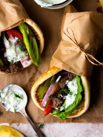 Easy Ground Beef Gyros are so delicious and ready in 30 minutes! Ground beef is perfectly seasoned with a greek spice blend then tucked inside of a soft pita with lots of fresh lettuce, tomato, cucumber, and red onion. Finish the gyro with homemade tzatziki sauce and feta cheese.