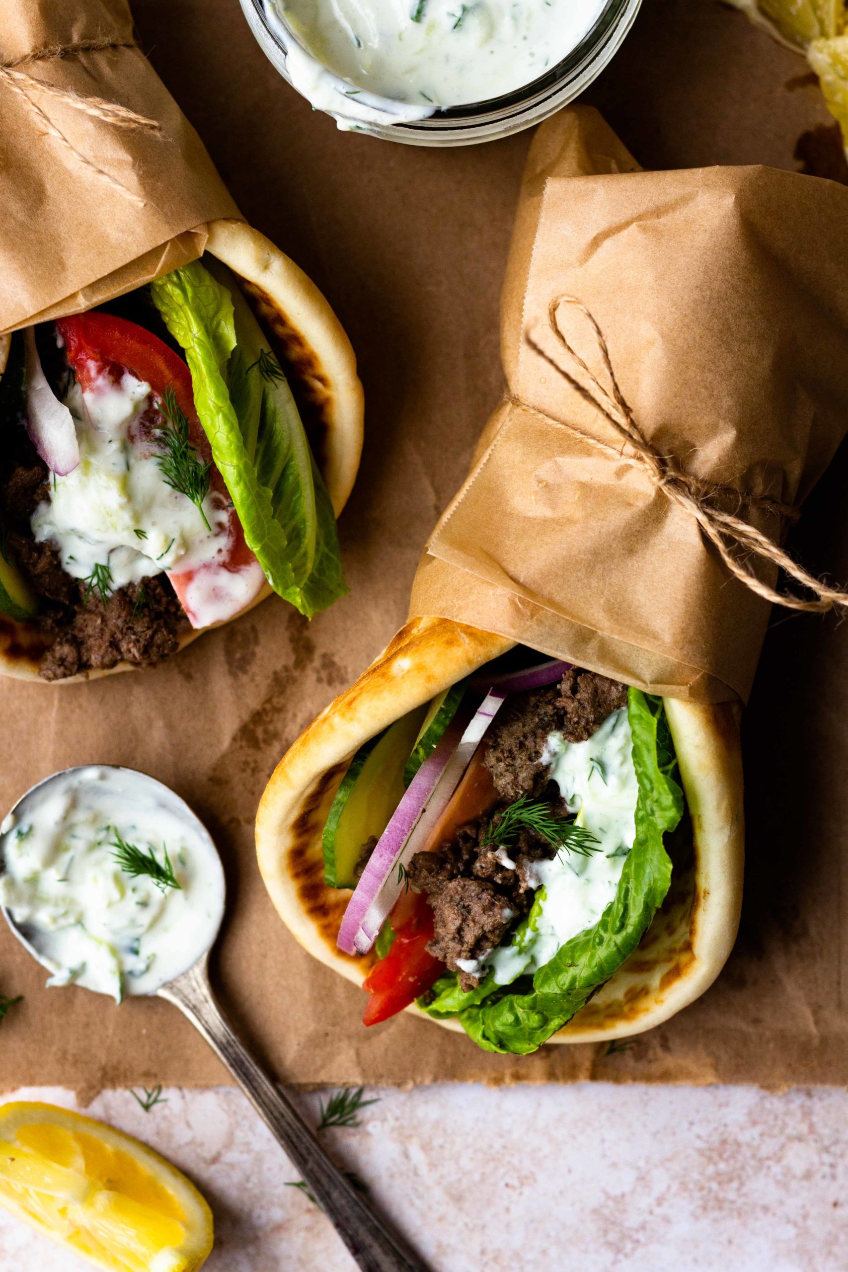 Easy Ground Beef Gyros are so delicious and ready in 30 minutes! Ground beef is perfectly seasoned with a greek spice blend then tucked inside of a soft pita with lots of fresh lettuce, tomato, cucumber, and red onion. Finish the gyro with homemade tzatziki sauce and feta cheese.