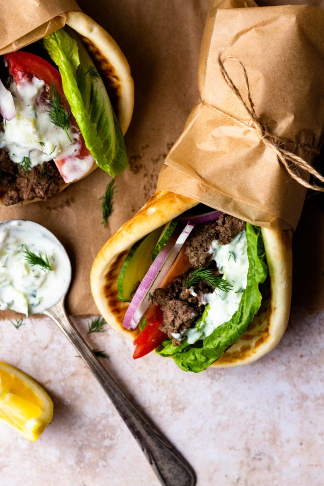 Easy Ground Beef Gyros are so delicious and ready in 30 minutes! Ground beef is perfectly seasoned with a greek spice blend then tucked inside of a soft pita with lots of fresh lettuce, tomato, cucumber, and red onion. Finish the gyro with homemade tzatziki sauce and feta cheese.