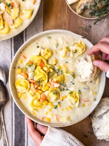 dipping bread in creamy chicken and cheese tortellini soup