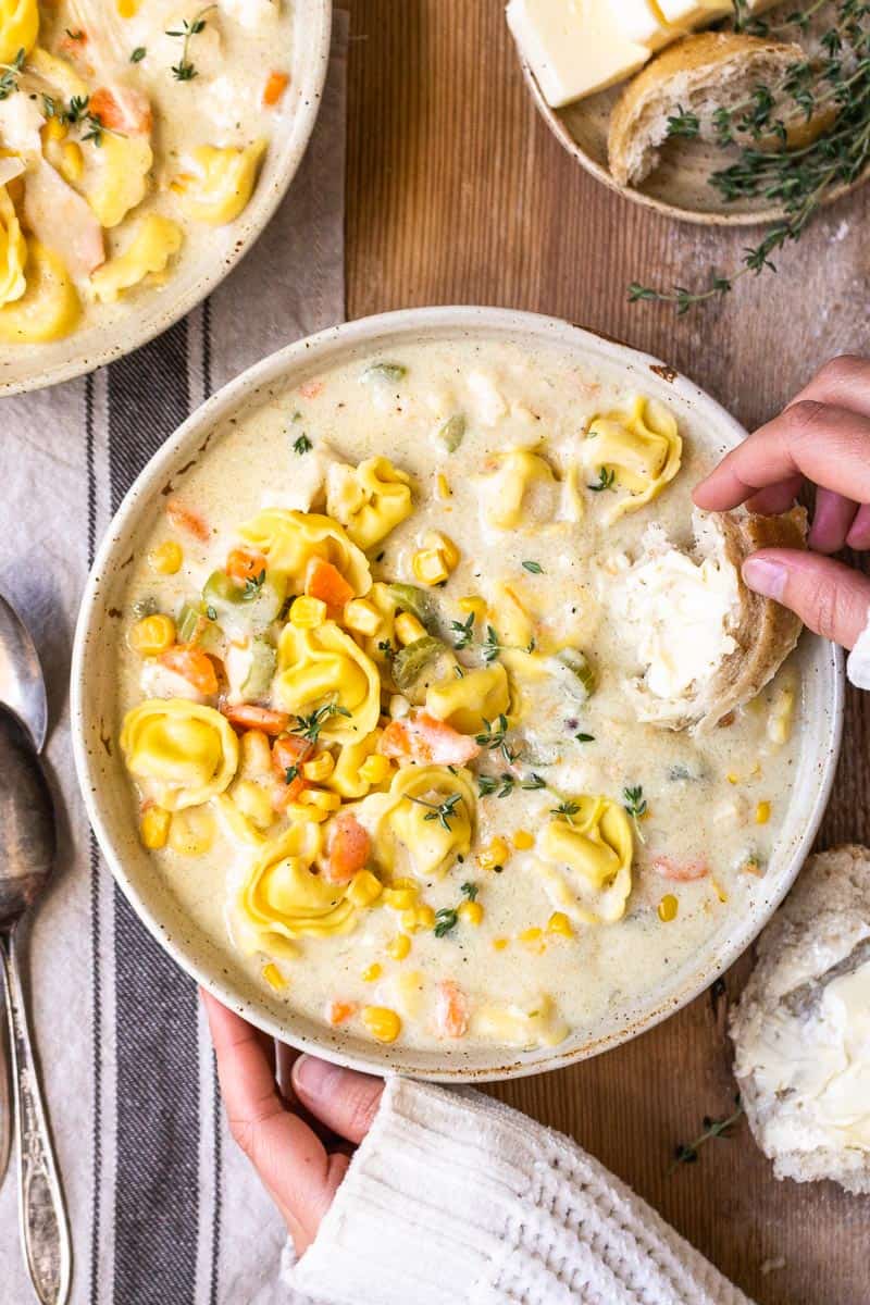 dipping bread in creamy chicken and cheese tortellini soup