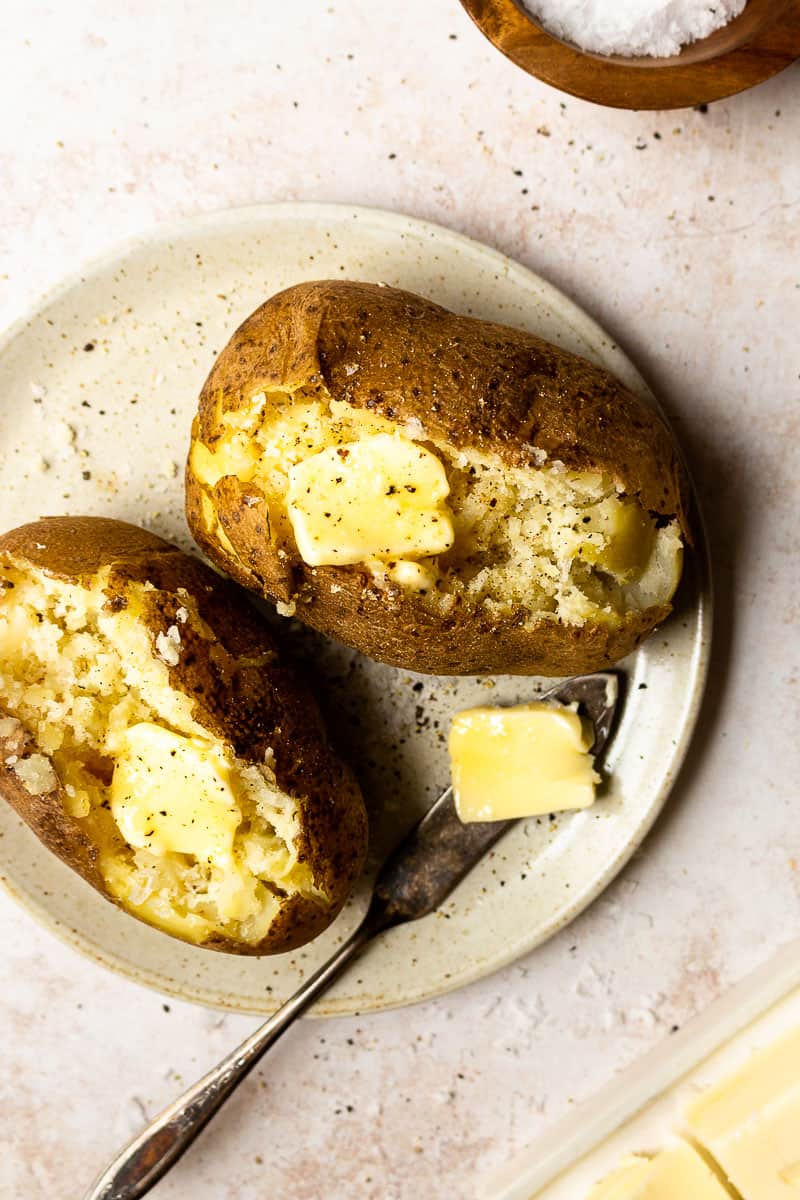 russet baked potatoes on plate with butter