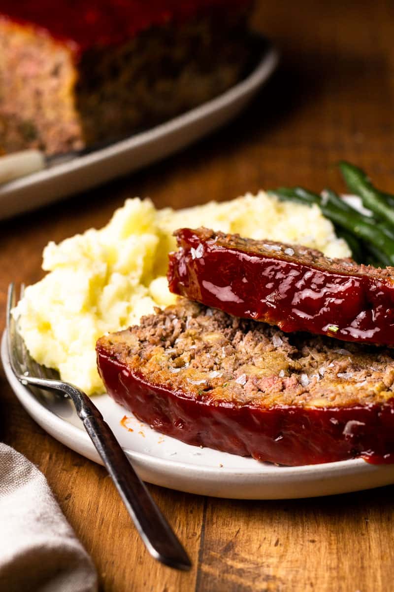 stuffing meatloaf on a plate with mashed potatoes and green beans