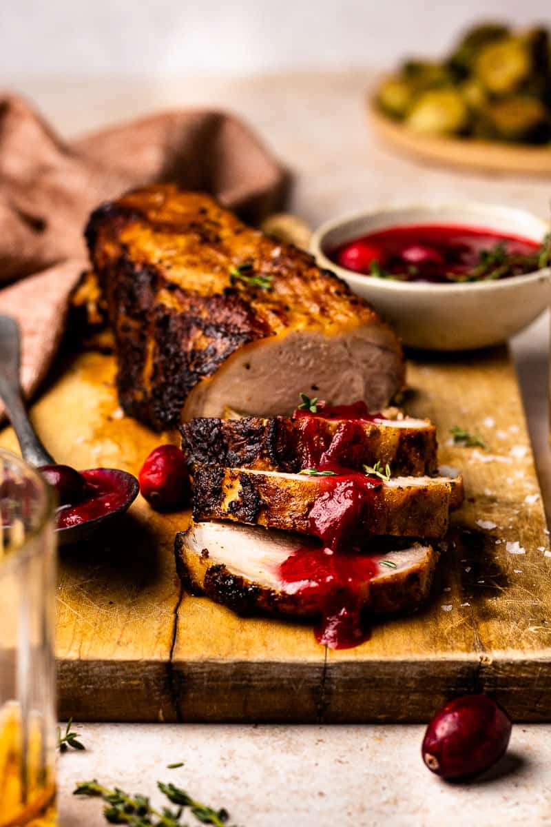 pork tenderloin sliced on a cutting board with cranberry glaze