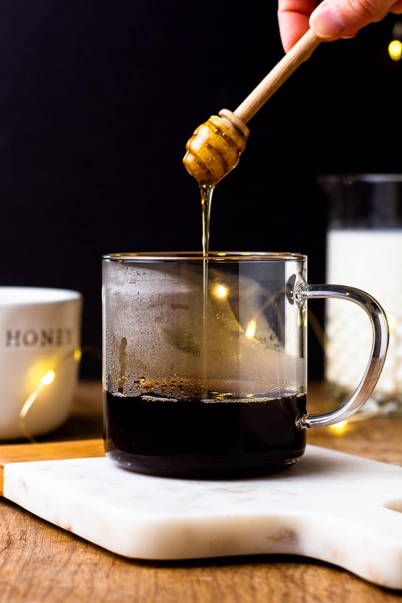 drizzling honey into a mug with espresso