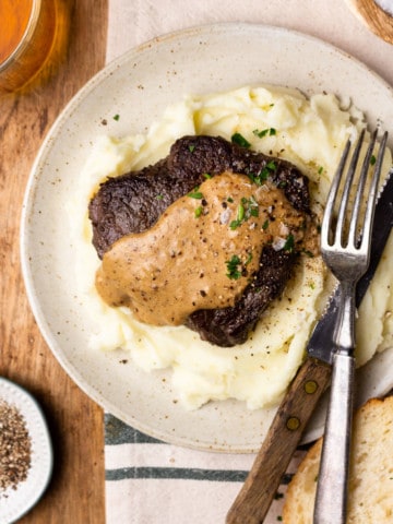 sirloin steak and mashed potatoes drizzled with bourbon peppercorn cream sauce