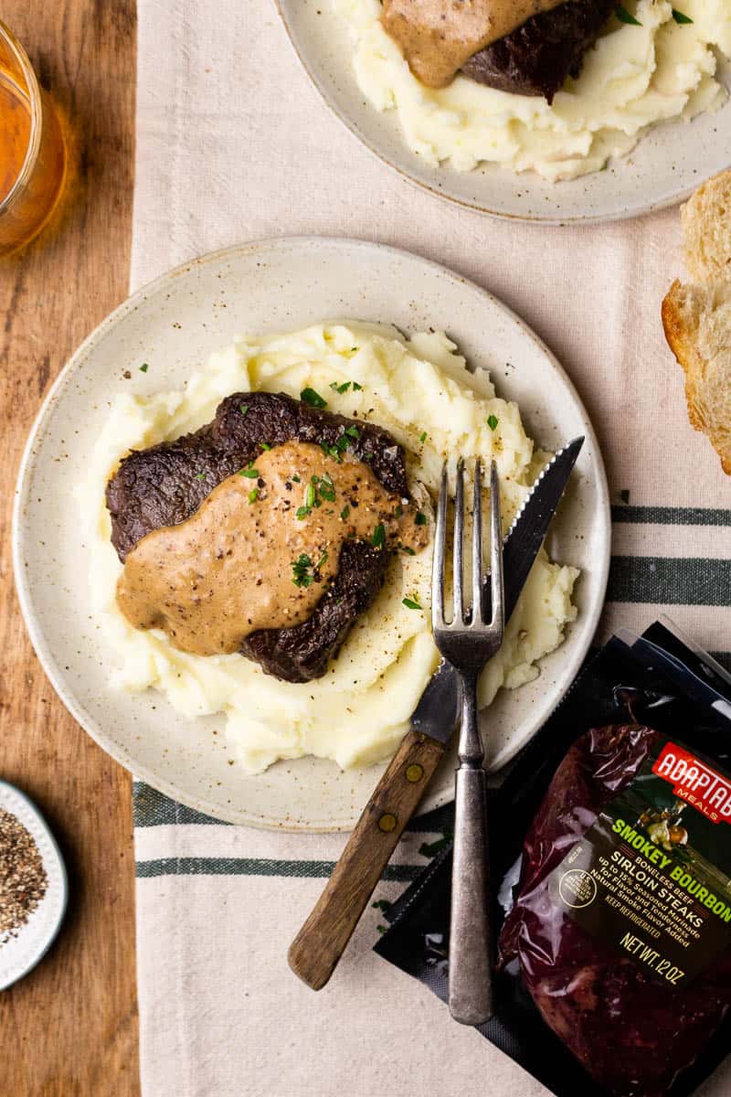 steak served with mashed potatoes and peppercorn sauce