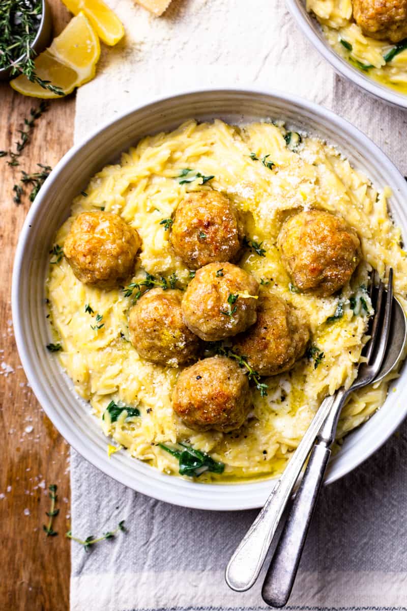 chicken meatballs over creamy spinach orzo in a bowl