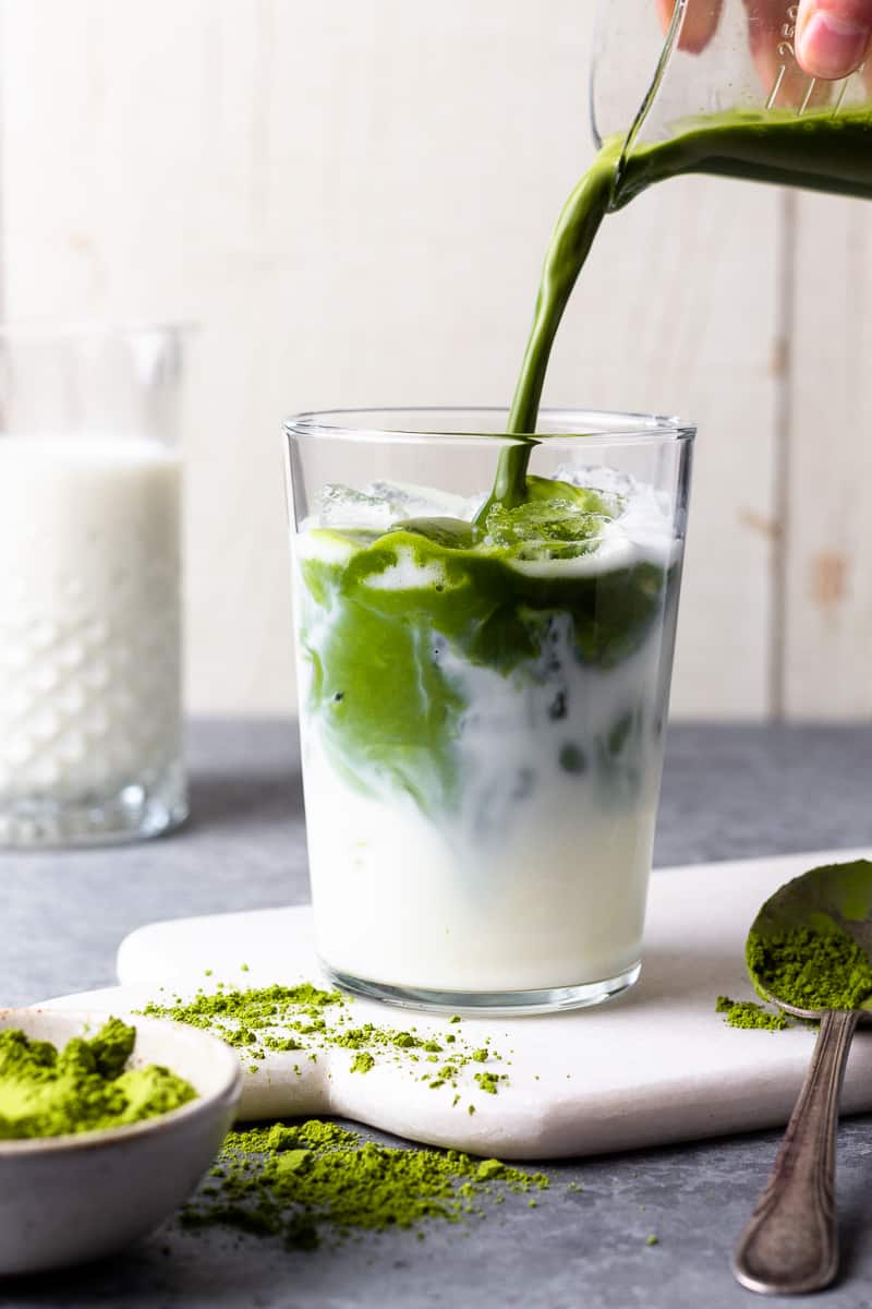 pouring matcha in a glass with ice and milk