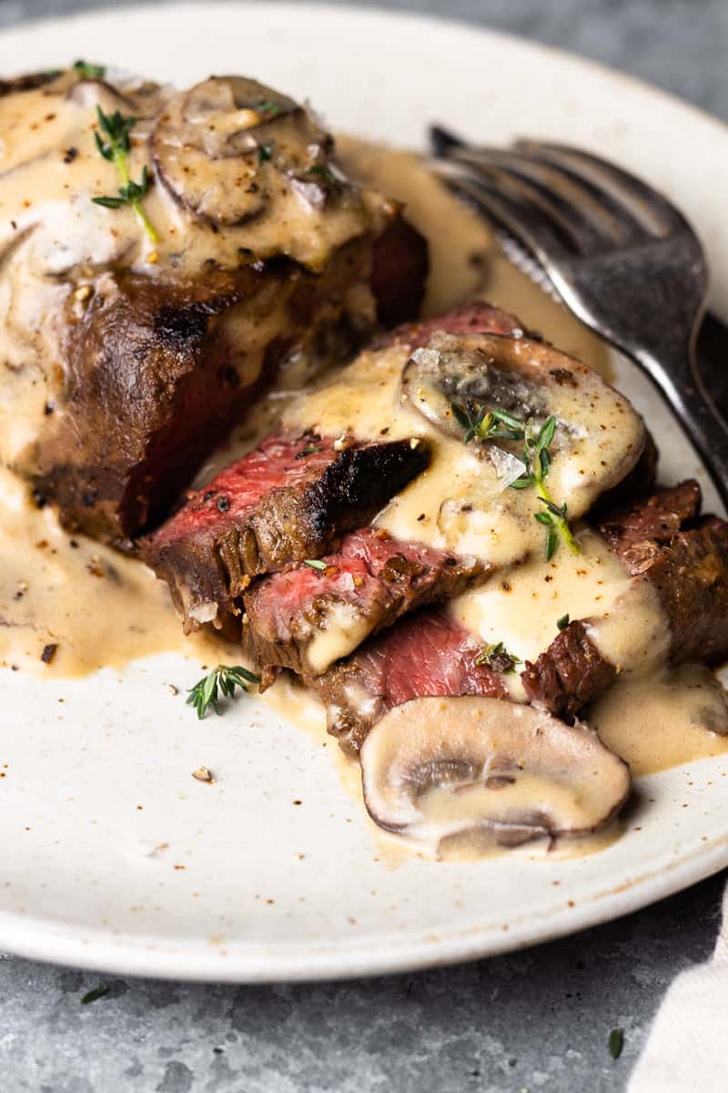 sliced venison steak on a plate with mushroom cream sauce