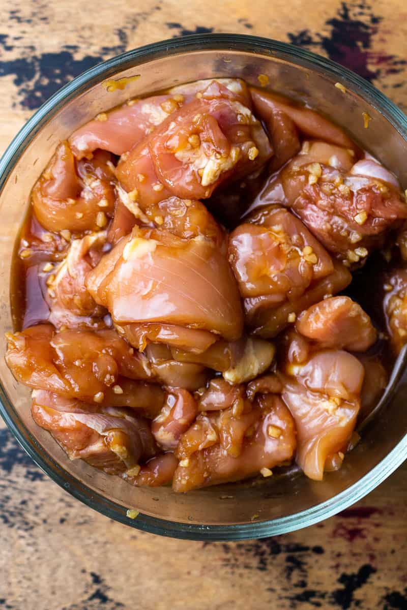 bite size pieces of uncooked chicken thighs in a bowl with marinade