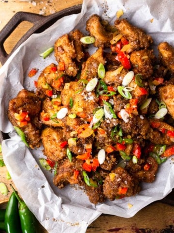 bite size fried chicken pieces on a serving dish with fried onion and peppers