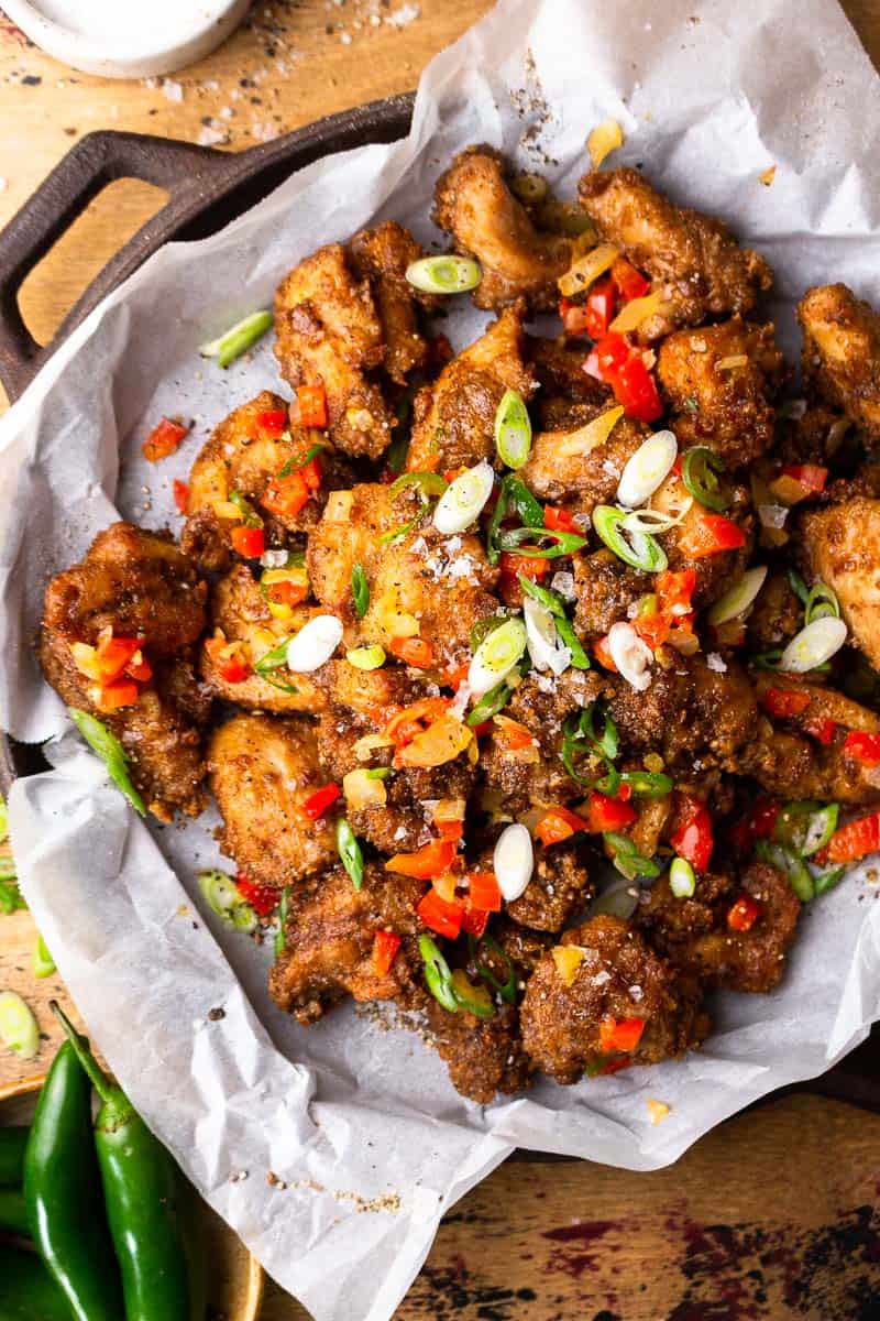 bite size fried chicken pieces on a serving dish with fried onion and peppers