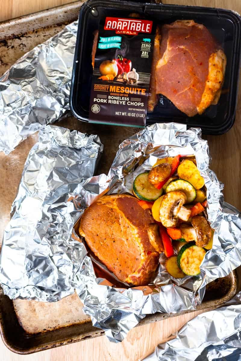 uncooked pork chops and vegetables in tinfoil packs