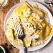lobster ravioli and lemon cream sauce on a plate and garnished with parsley