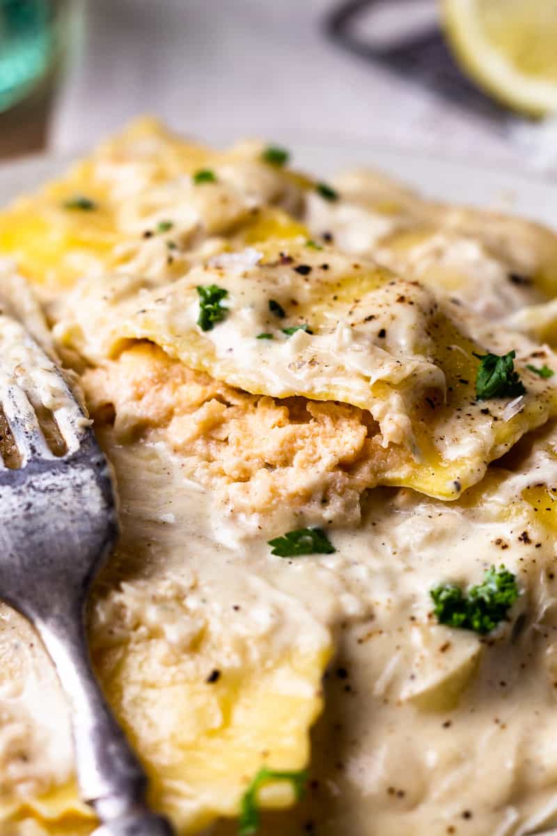lobster ravioli with lemon cream sauce on a plate with one ravioli cut in half