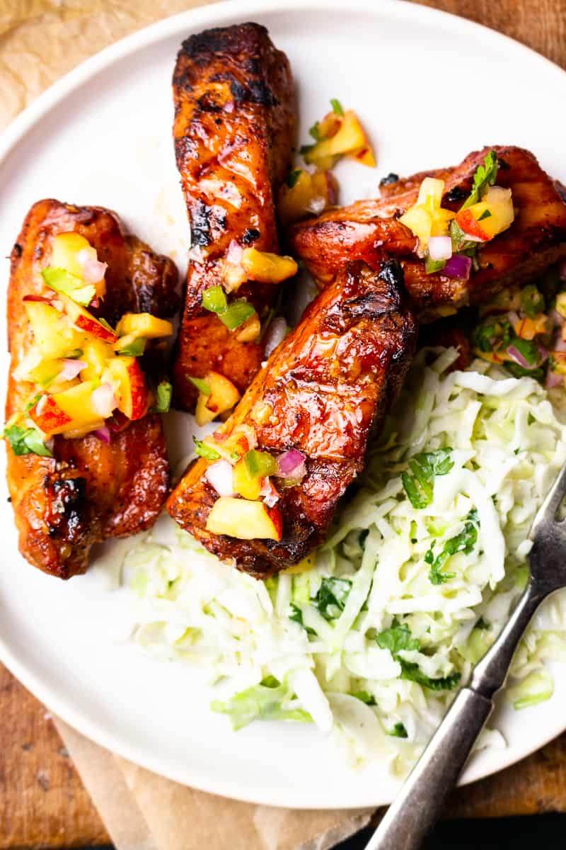 grilled boneless pork ribs on a plate with coleslaw and peach pico de gallo