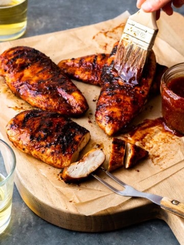 slathering smoked chicken breasts with bbq sauce