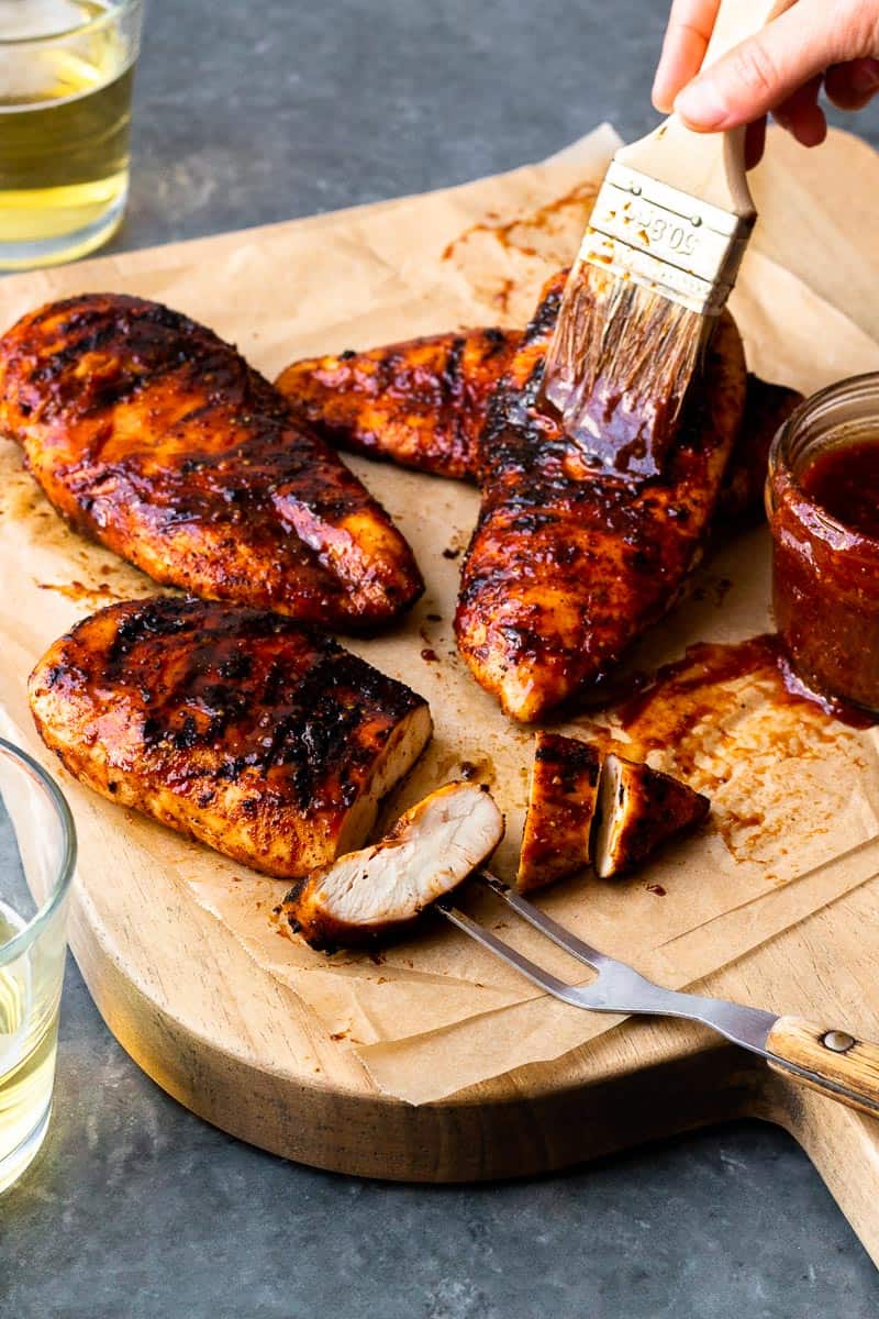 slathering smoked chicken breasts with bbq sauce