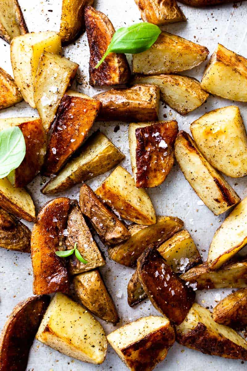 roasted potatoes on a sheet pan with salt and fresh basil