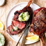 sliced bison tomahawk steak with chimichurri butter on top