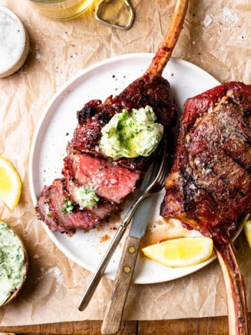 sliced bison tomahawk steak with chimichurri butter on top
