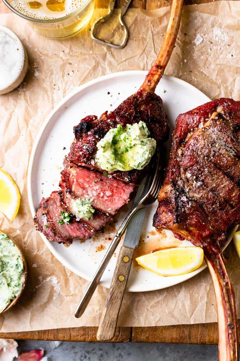 sliced bison tomahawk steak with chimichurri butter on top