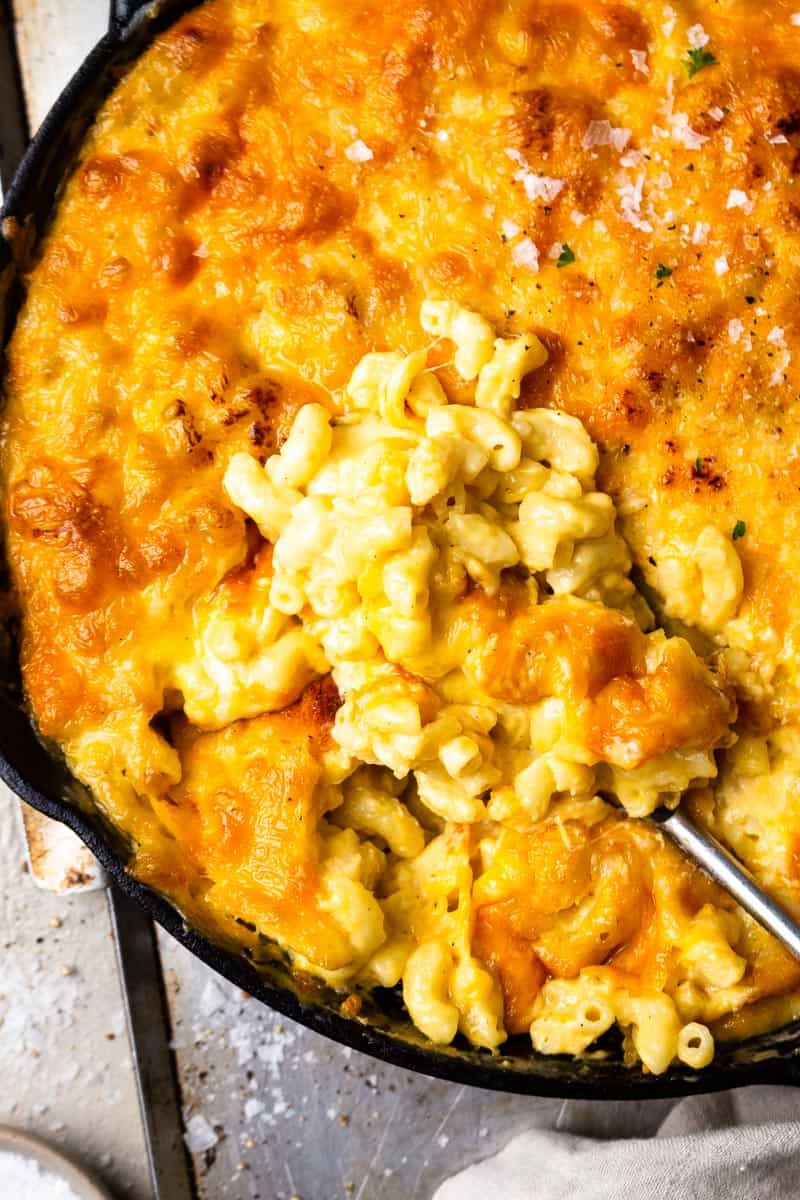 scooping mac and cheese from a skillet