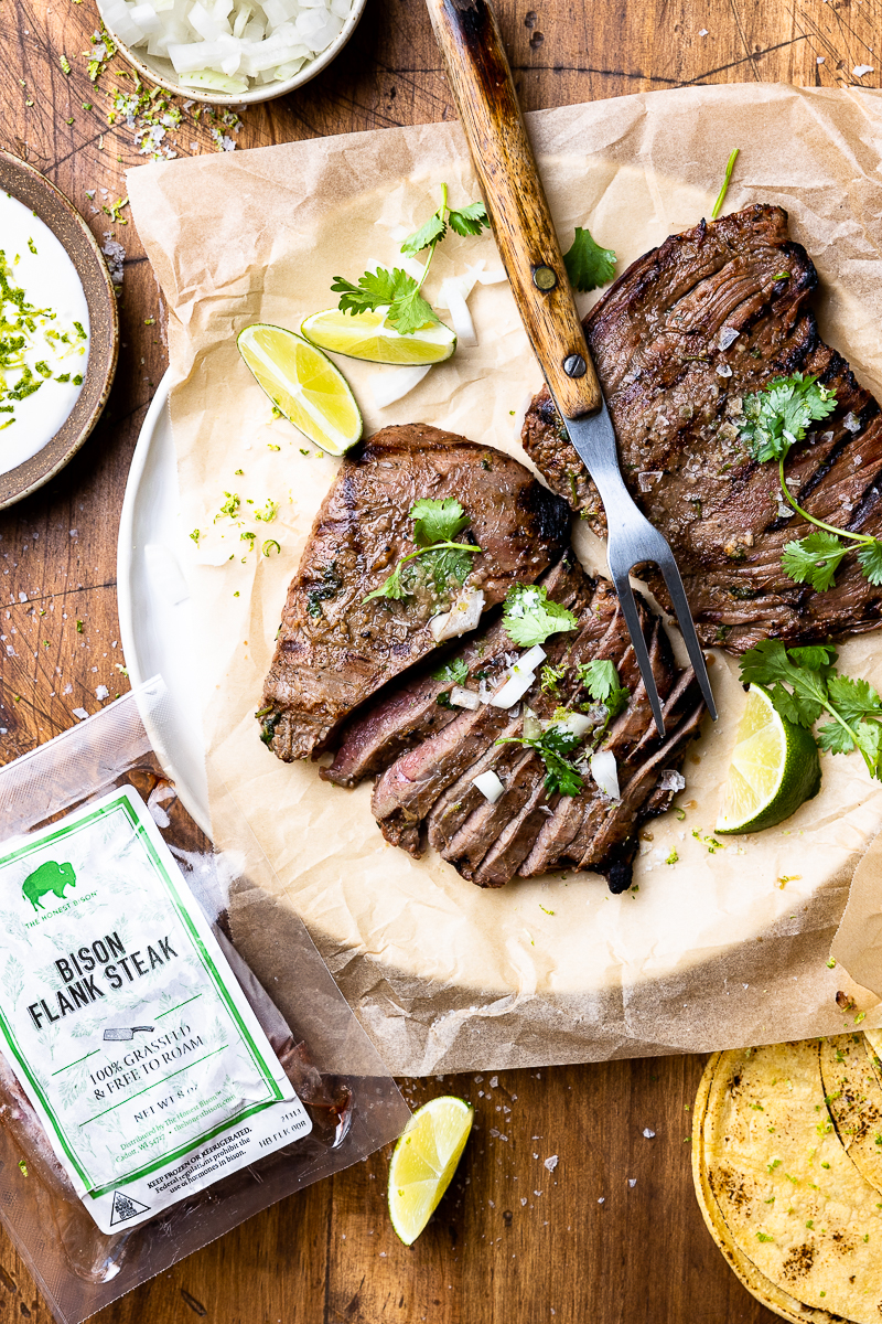 grilled flank steaks on a plate with lime wedges