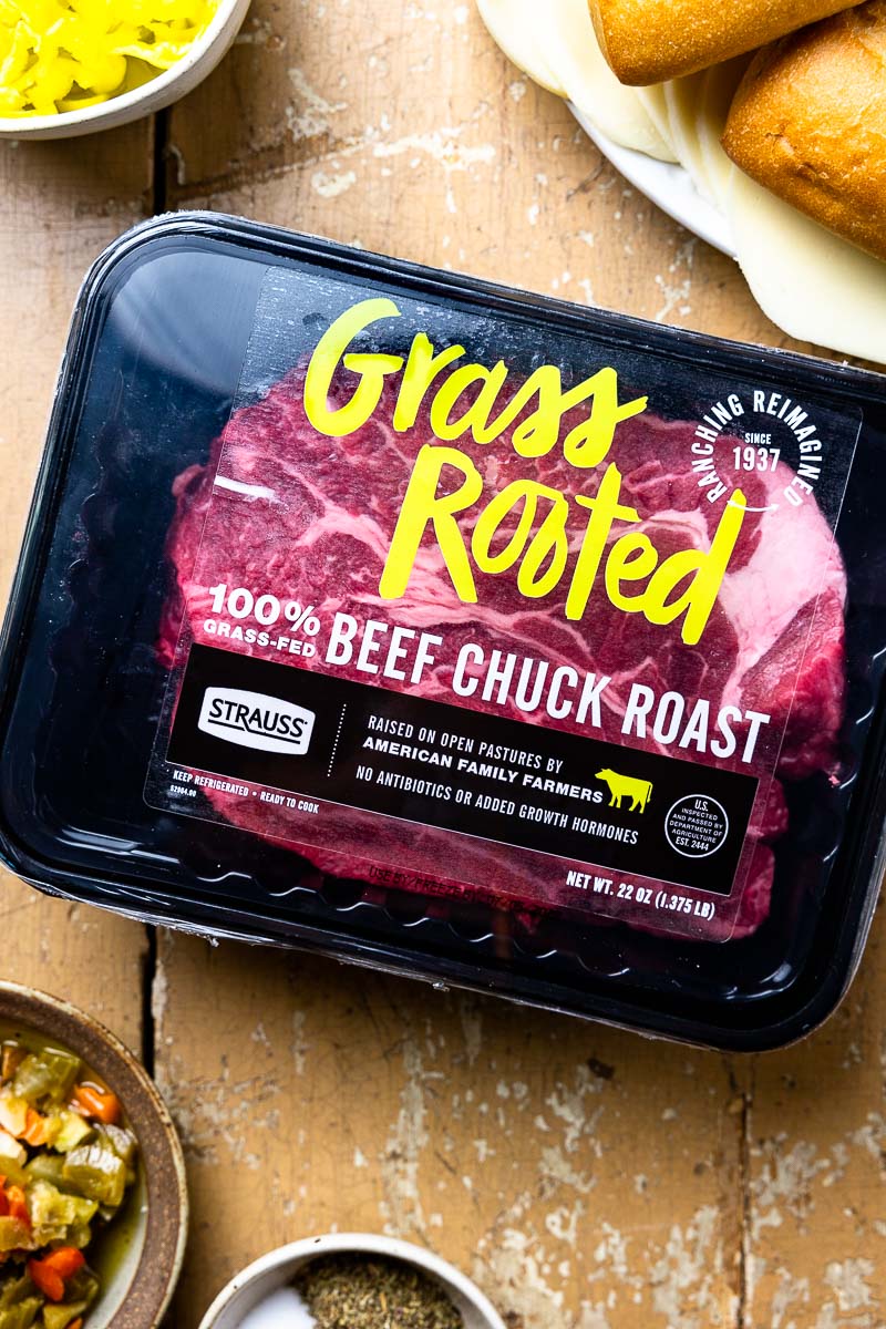 Grass Rooted beef chuck roast in packaging surrounded by pickled vegetables, bread and cheese
