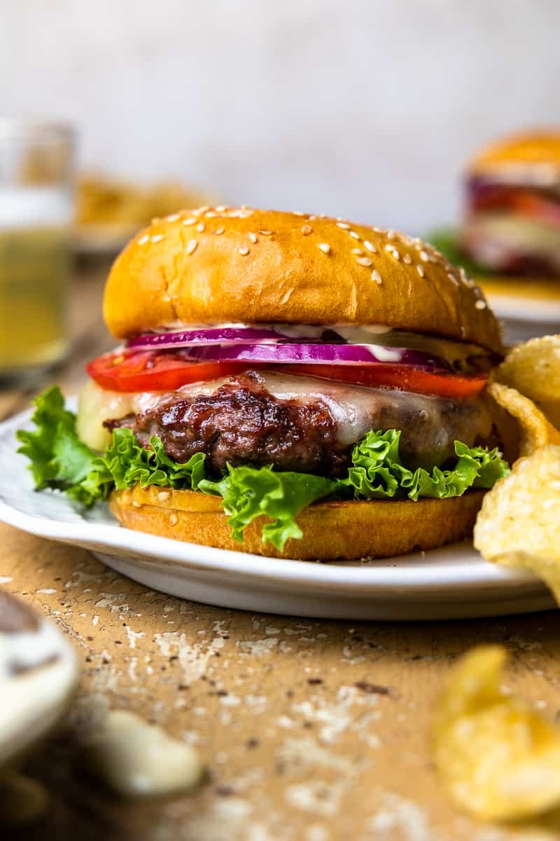 elk burger topped with tomato, red onion, lettuce, cheese and mustard aioli