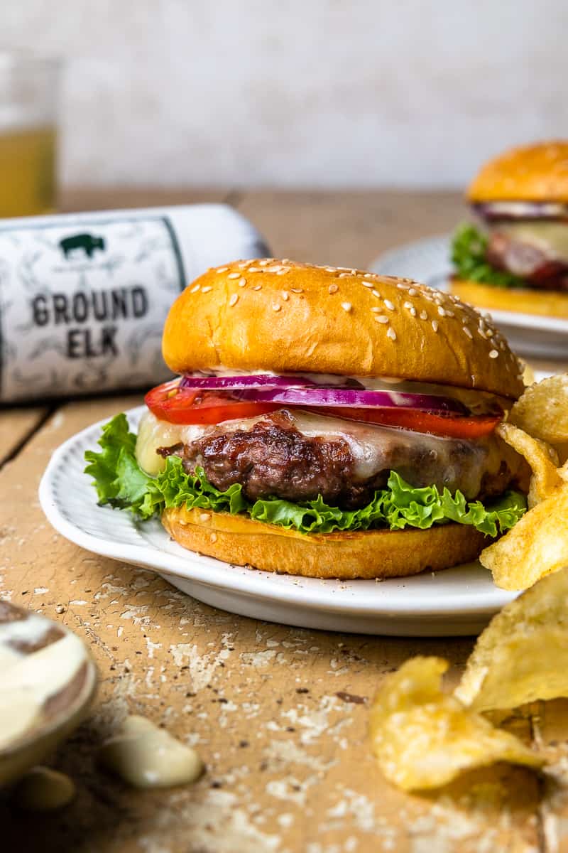 elk burger on a plate with a package of The Honest Bison Ground Elk in the background