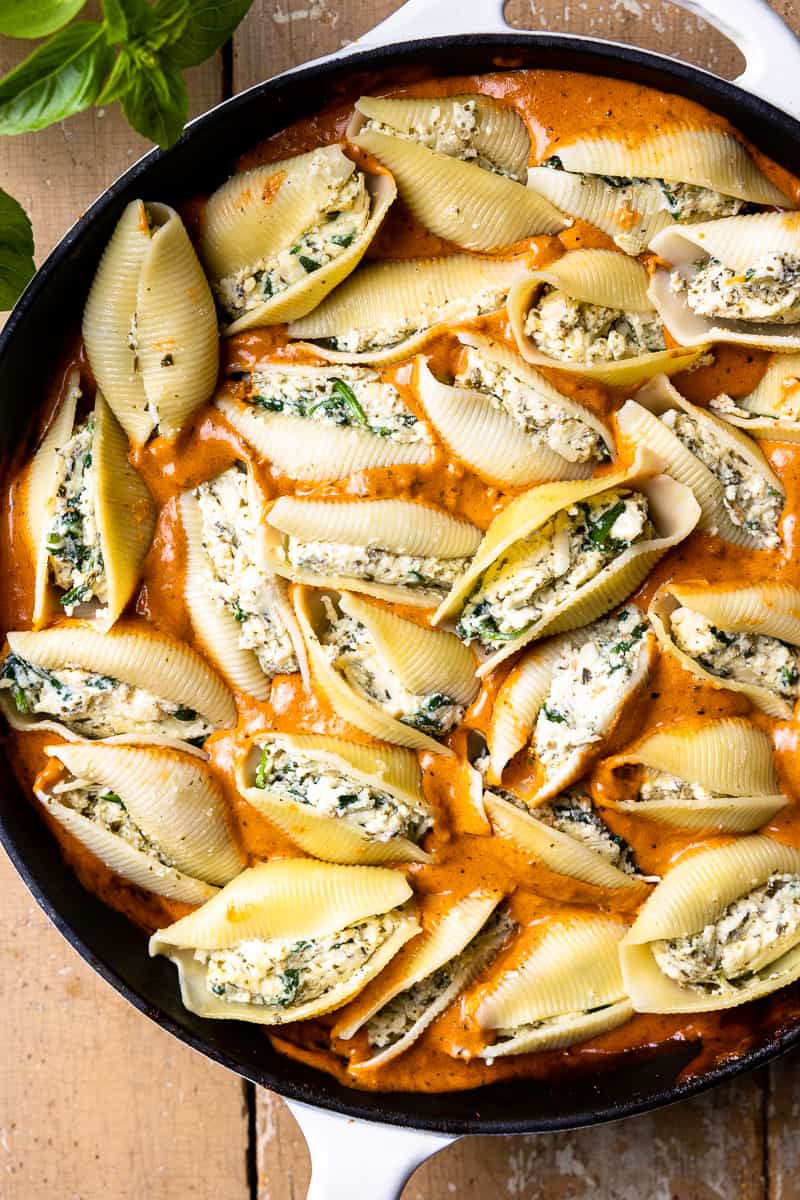 Uncooked stuffed pasta shells in a skillet with vodka sauce