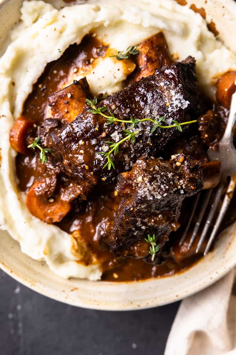 red wine braised bison short ribs with carrots over mashed potatoes in a bowl