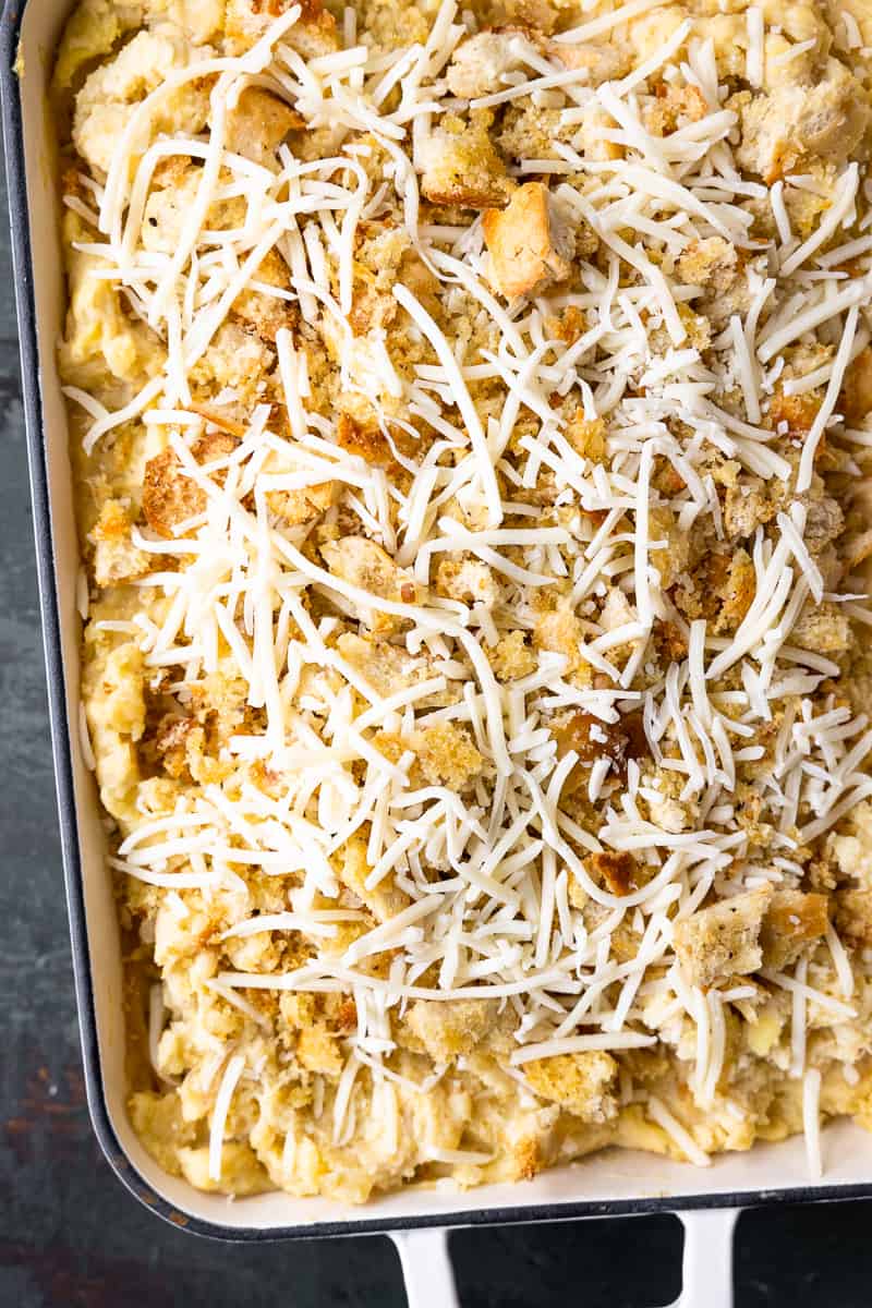 unbaked cheesy caramelized onion mashed potato bake in a baking dish topped with cheese and parmesan bread crumbs
