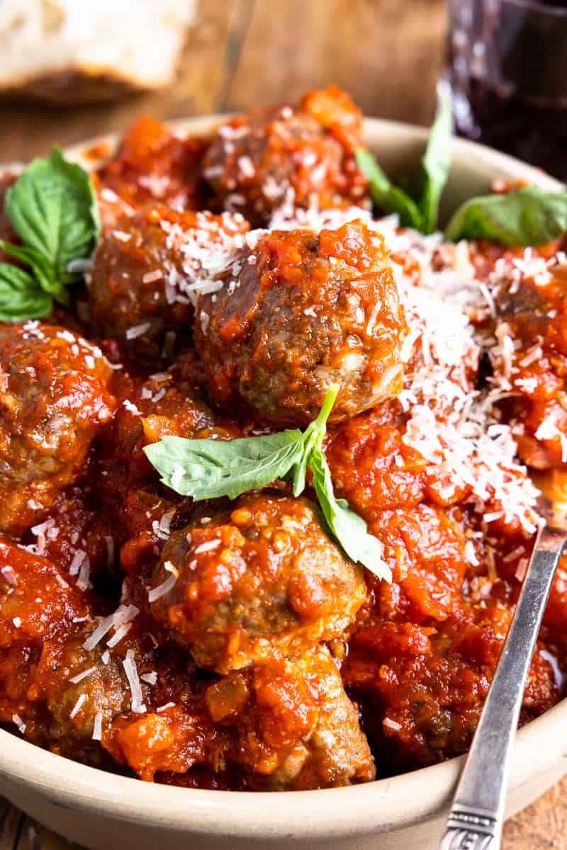 venison meatballs in a bowl with tomato sauce, parmesan and fresh basil