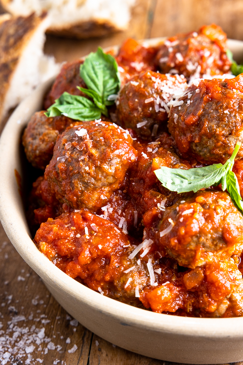 venison meatballs in a bowl with tomato sauce, parmesan and fresh basil