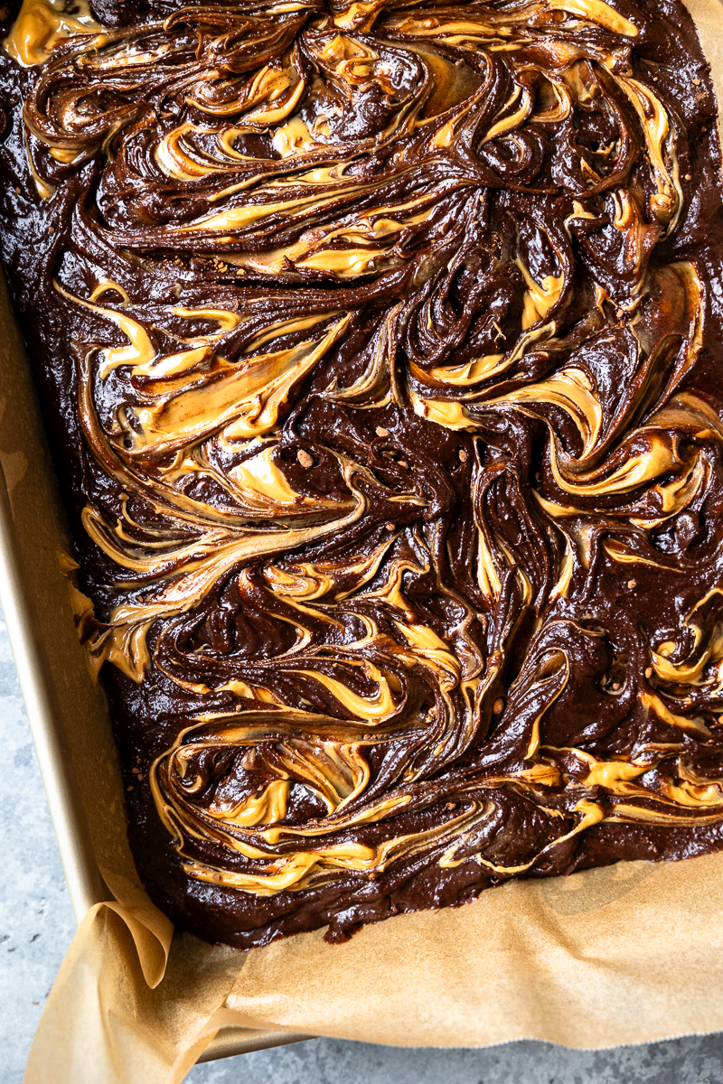 Brownie batter in a baking dish swirled with peanut butter
