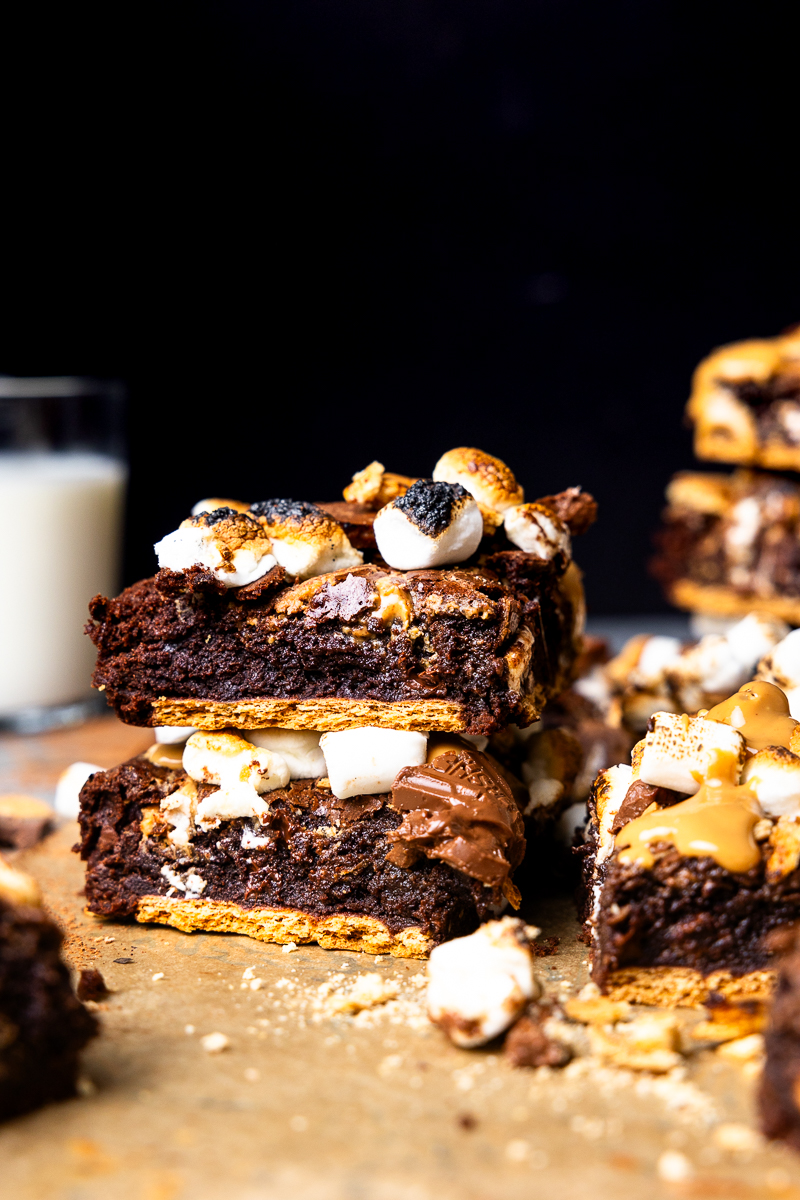 two s'mores brownies stacked next to a glass of milk