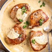 four pork chops in a skillet with dijon cream sauce