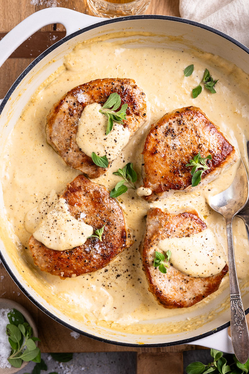 four pork chops in a skillet with dijon cream sauce