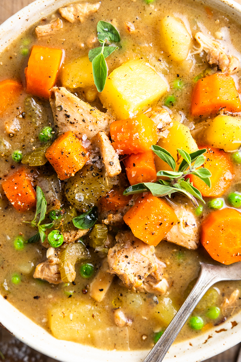 close up of chicken stew in a bowl garnished with fresh oregano