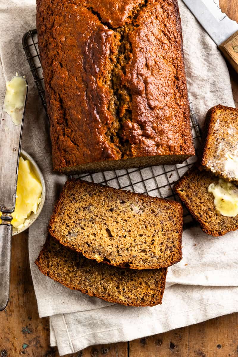 sliced sourdough banana bread on a cutting board with a butter dish