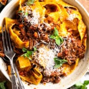 Venison ragu served in a pasta bowl with parmesan cheese and garnished with fresh oregano.