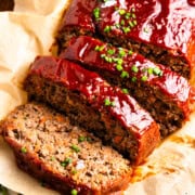 Meatloaf with slices next to a pinch bowl of salt and a glass of red wine.