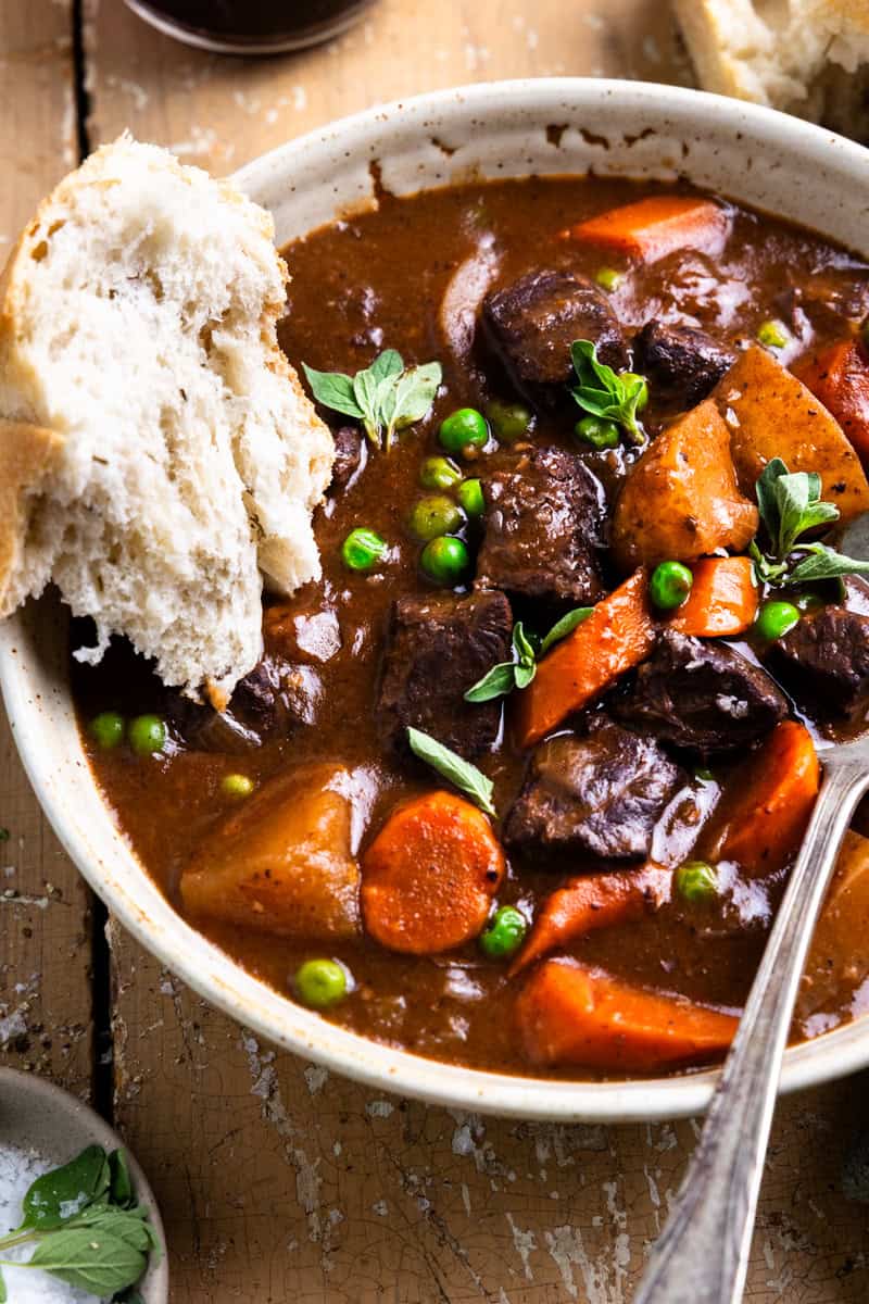 Dipping a piece of bread into a bowl of stew.